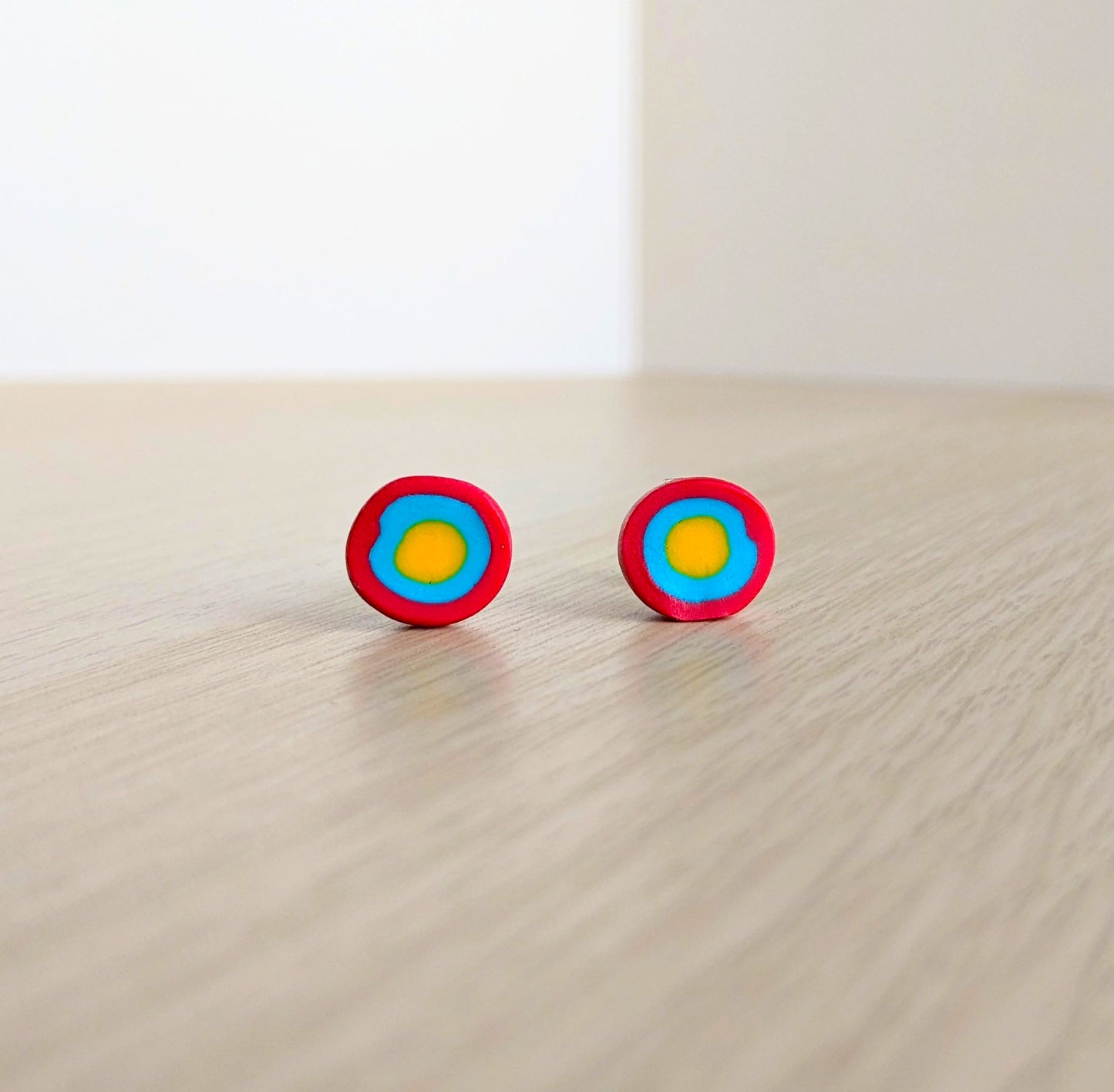 Handmade gobstopper stud earrings made from red, blue and yellow clay. Handmade by luxury gifts and stationery brand, Bella & The Moon