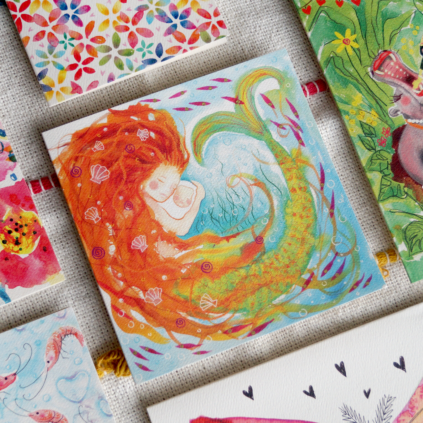 Mermaid mummy & baby greetings card featuring a warm embrace of a mother mermaid and her baby. Perfect for baby showers, Christenings, new mum's and Mother's Day. 14cm x 14cm in size and printed on premium quality 300gsm card. Designed by luxury gifts and stationery brand, Bella & The Moon.