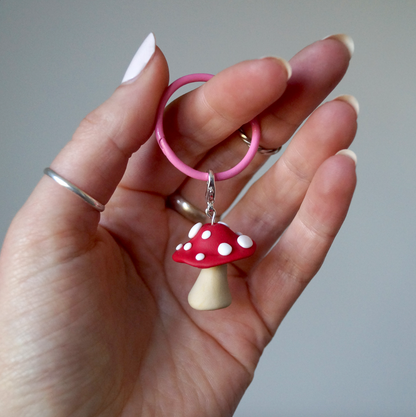 A handmade polymer clay keyring in the shape of a red and white mushroom, held by a hand. Bella & The Moon gifts and stationery