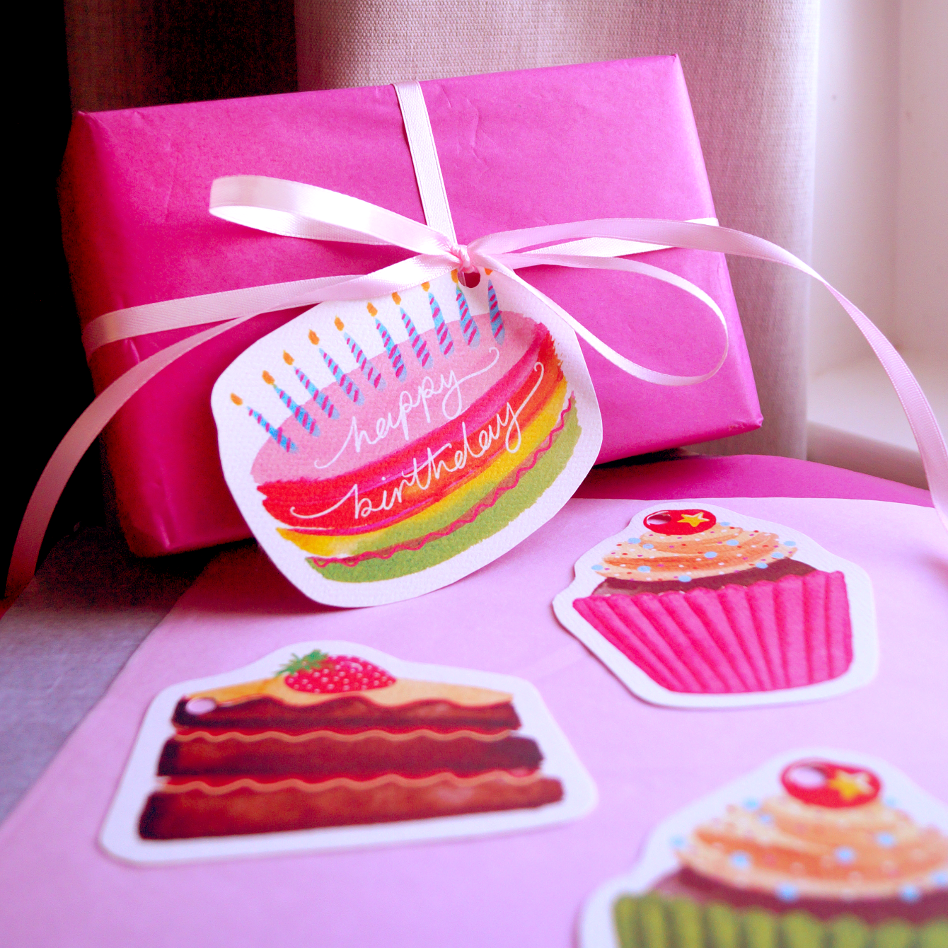 Birthday cake gift tags tied to a pink gift. Present and gift wrapping. Unique and funny gifting ideas. Bella & The Moon gifts and stationery