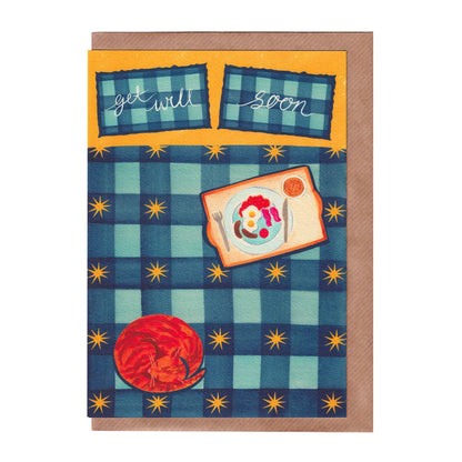 Greeting card featuring a blue checkered bed with yellow stars. The bed has a ginger cat on it and a yummy English breakfast on a tray. It also features 'get well soon' text. A5 is size and printed on premium quality 300gsm card stock. Designed by luxury gifts and stationery brand, Bella & The Moon. 