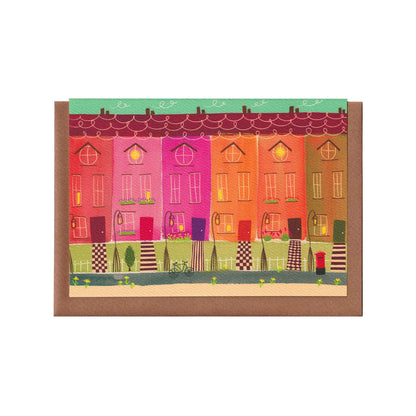 A colourful card featuring a line of attached houses with lampposts and victorian-style tiled paths. A warming scene. A card for any occasion. A6 in size. Bella & The Moon gifts and stationery.