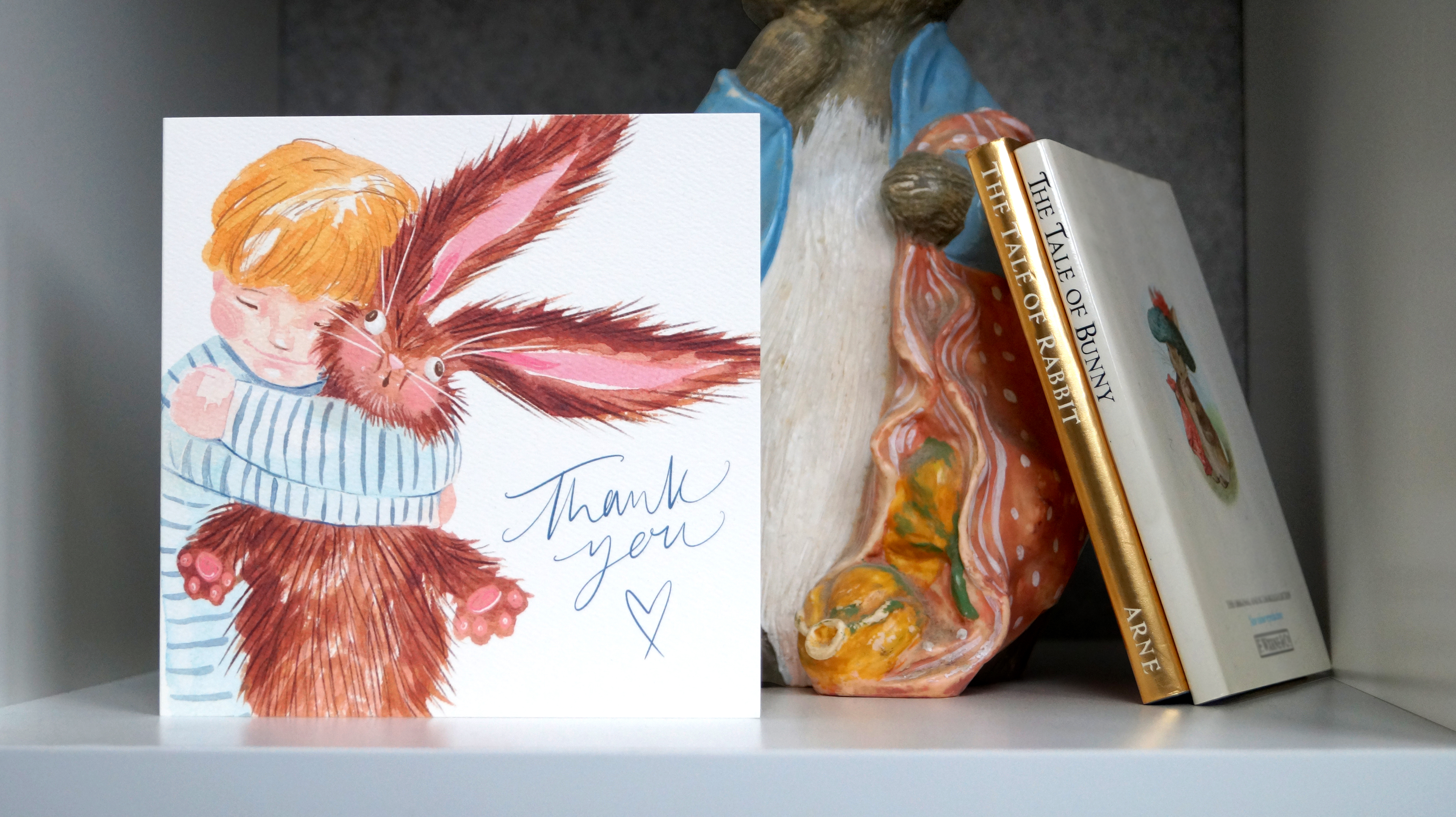 Thank You greetings card inspired by cuteness aggression, featuring a comical, heart warming, blonde child hugging a fluffy rabbit. Perfect for saying thank you. 14cm x 14cm, square in size and printed on premium quality 300gsm card stock. Designed by luxury gift and stationery brand, Bella & The Moon.