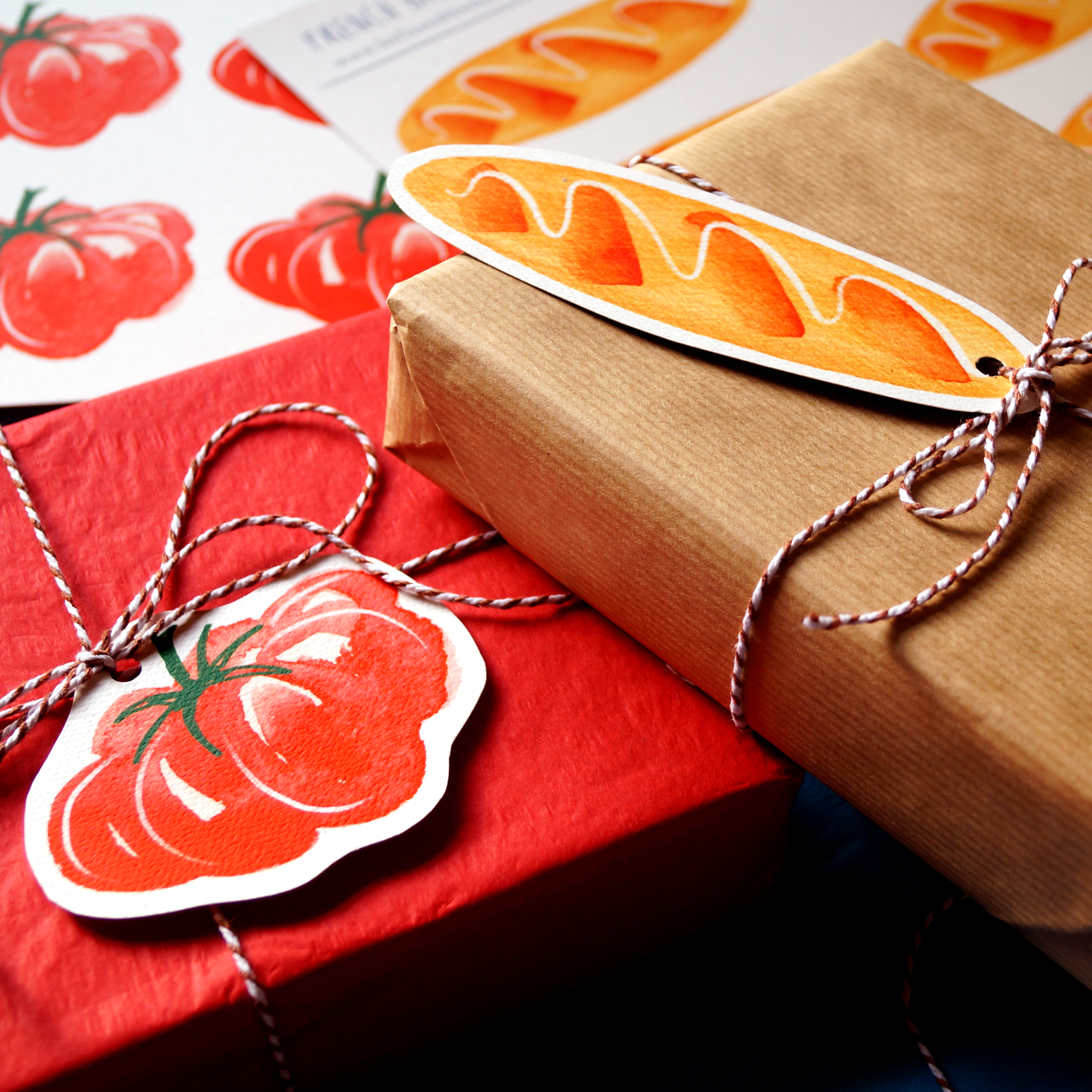 A tomato gift tag and a baguette gift tag tied to red and brown gifts with string. Present and gift wrapping. Unique and funny gifting ideas. Bella & The Moon gifts and stationery