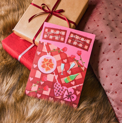 You're My Dream Come True, romantic bed spread greetings card. Featuring a pink and read quilted, double bed covered in roses, cookies, chocolates and a love potion. Perfect for Valentine's Day, anniversaries, engagements, celebrating love, girlfriends and boyfriends. A5 is size and printed on premium quality 300gsm card stock. Designed by luxury gifts and stationery brand, Bella & The Moon. 